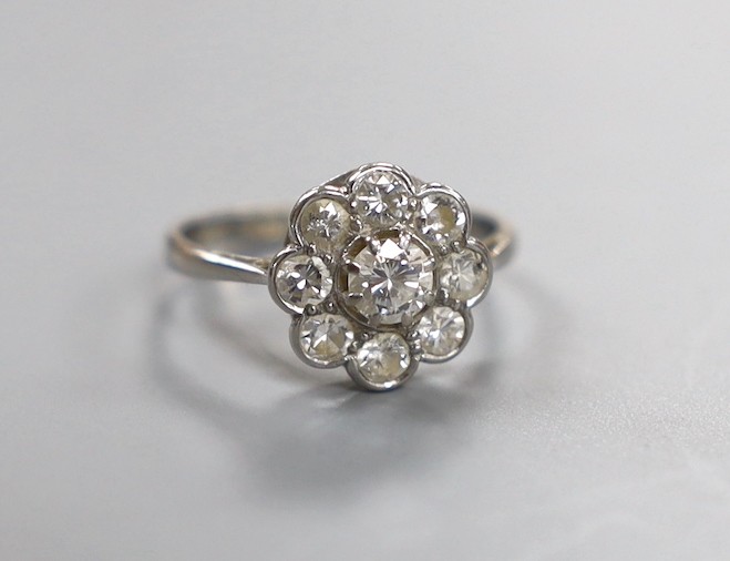 An 18ct, plat and nine stone diamond set flower head cluster ring, size L, gross weight 2.4 grams.